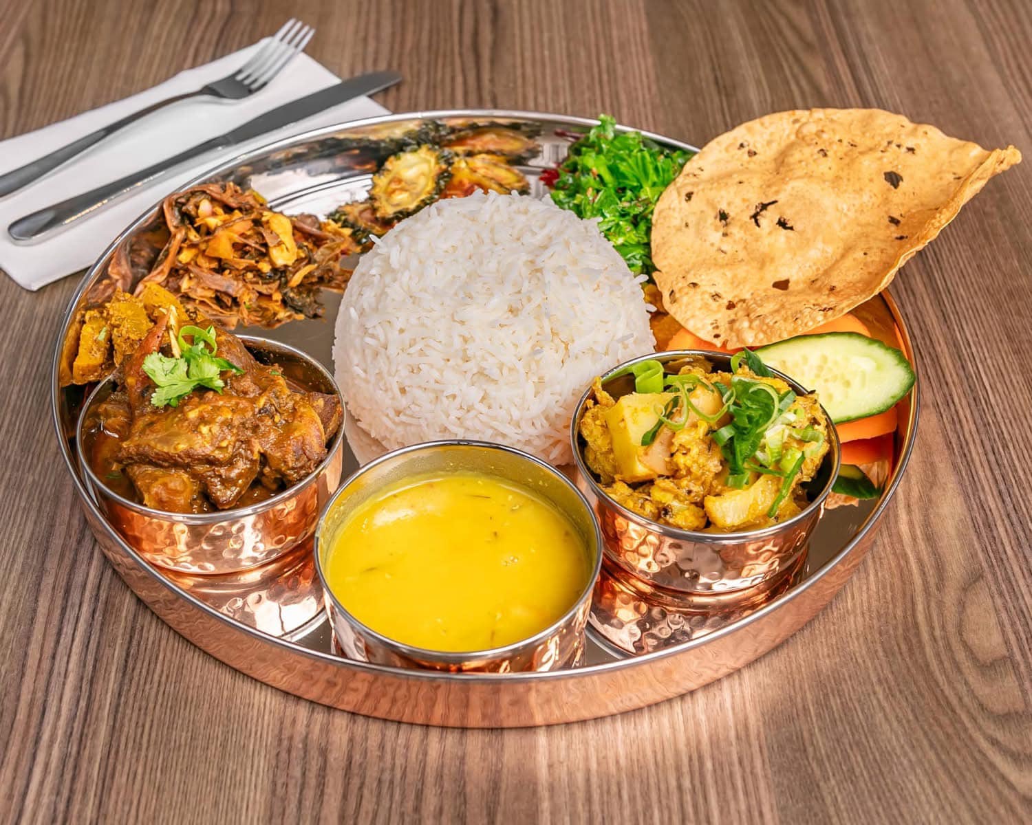 Traditional Nepali thali set with rice, lentils, vegetables, greens, pickle and papad