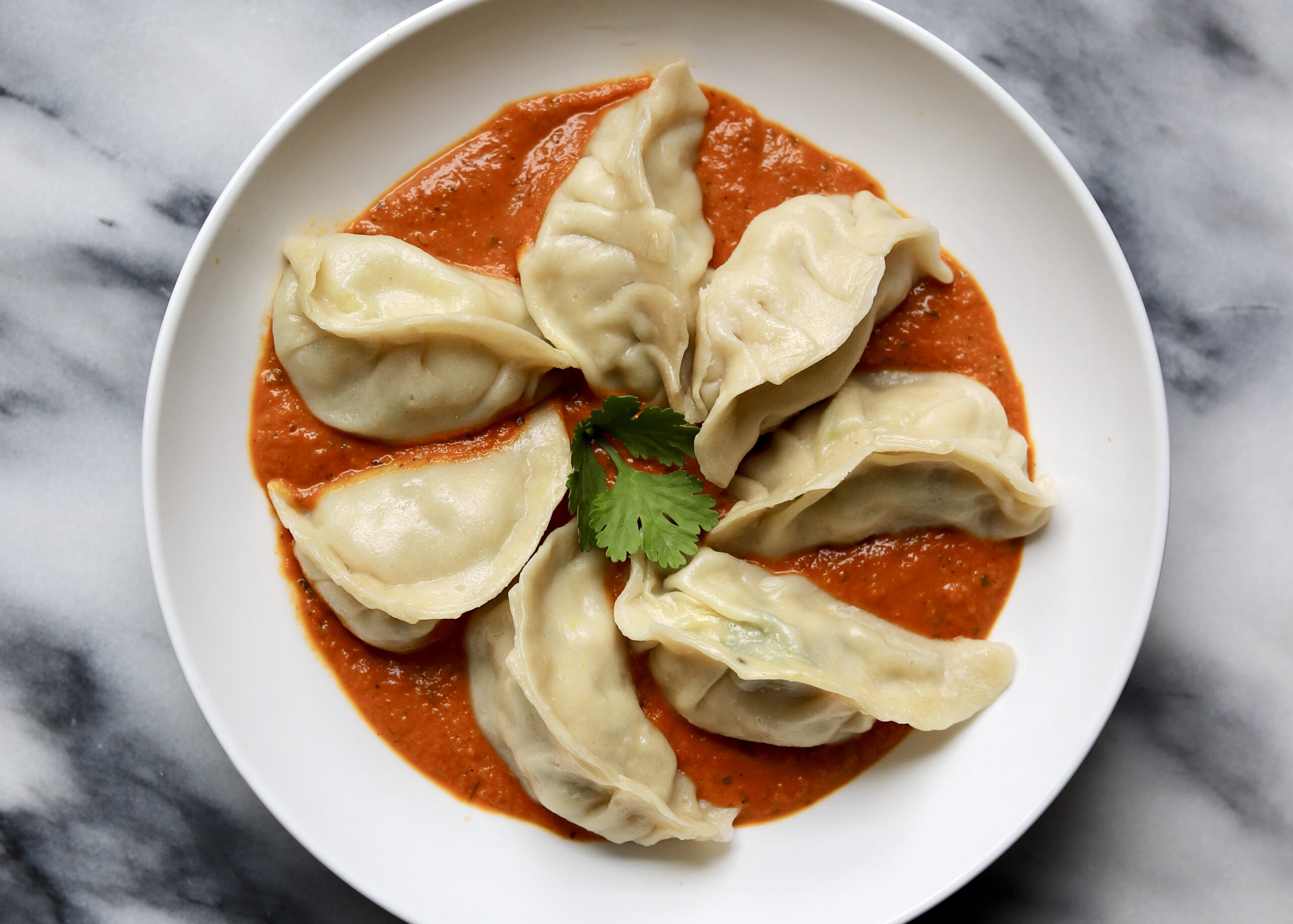 Chicken momo dumplings with spicy tomato sesame chutney